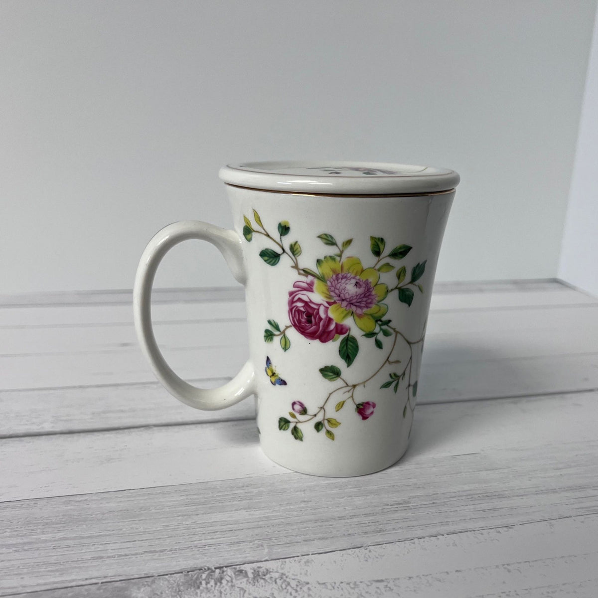 White mug with floral design on a light wooden surface