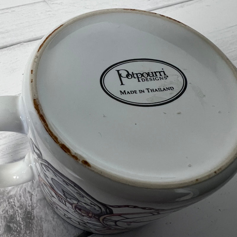 Mug with 'Potpourri Designs' logo on a white wooden surface