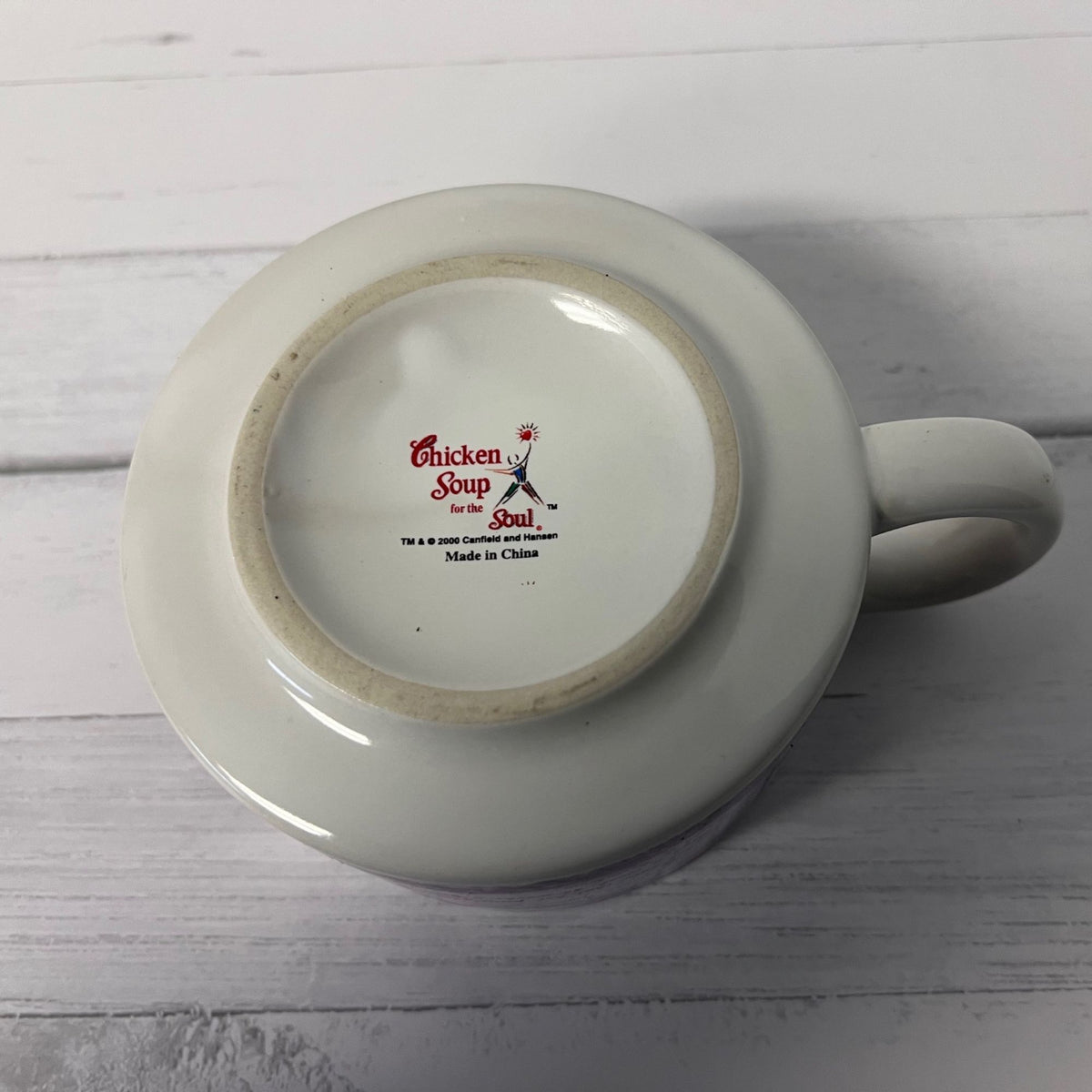 White mug with 'Chicken Soup for the Soul' logo on a wooden surface