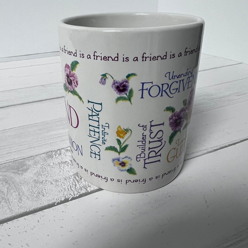 White mug with floral designs and text on a white wooden surface