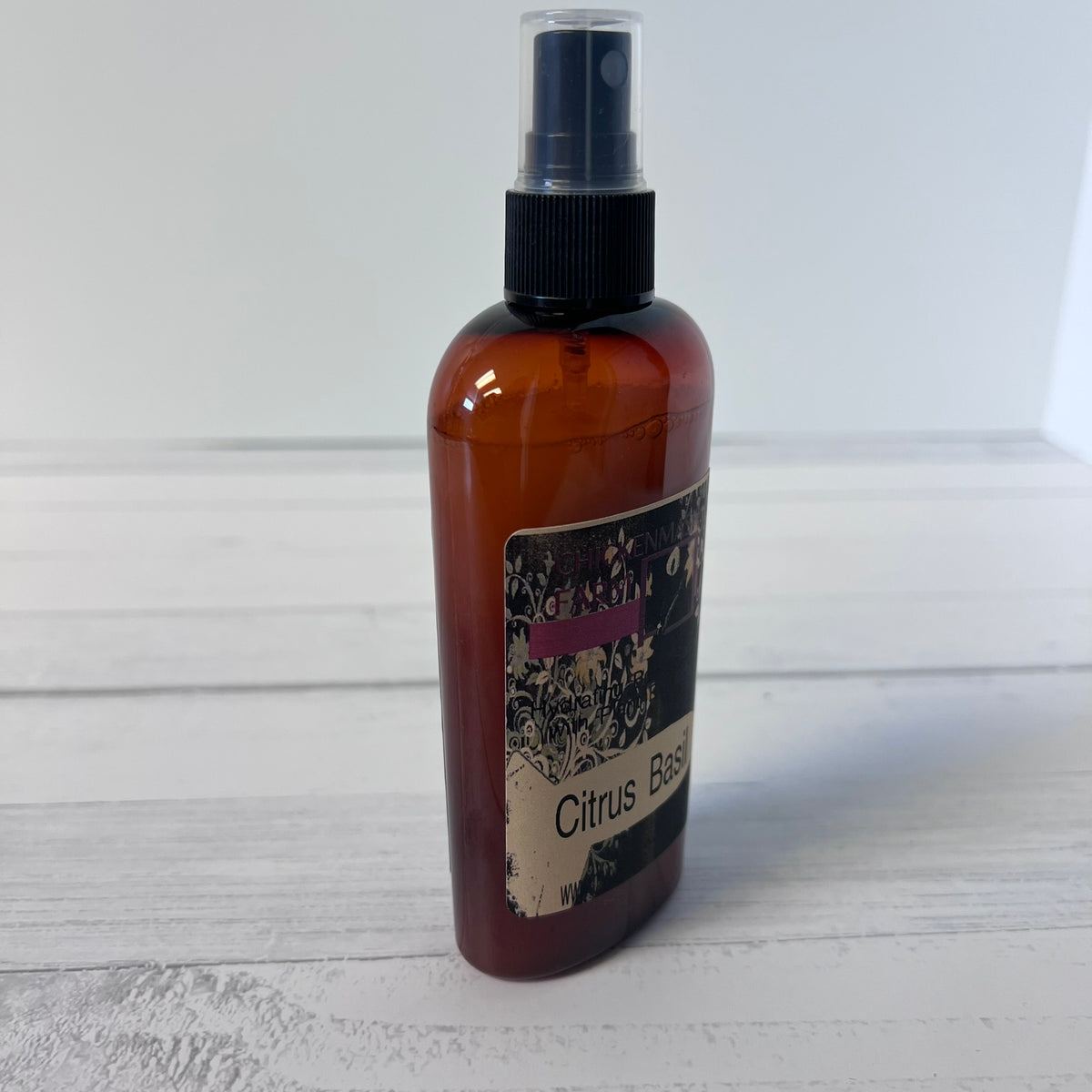 An amber spray bottle with a black spray cap and a decorative label reading 'Citrus B.