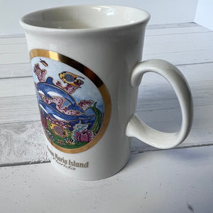 White mug with decorative fish design on a white surface