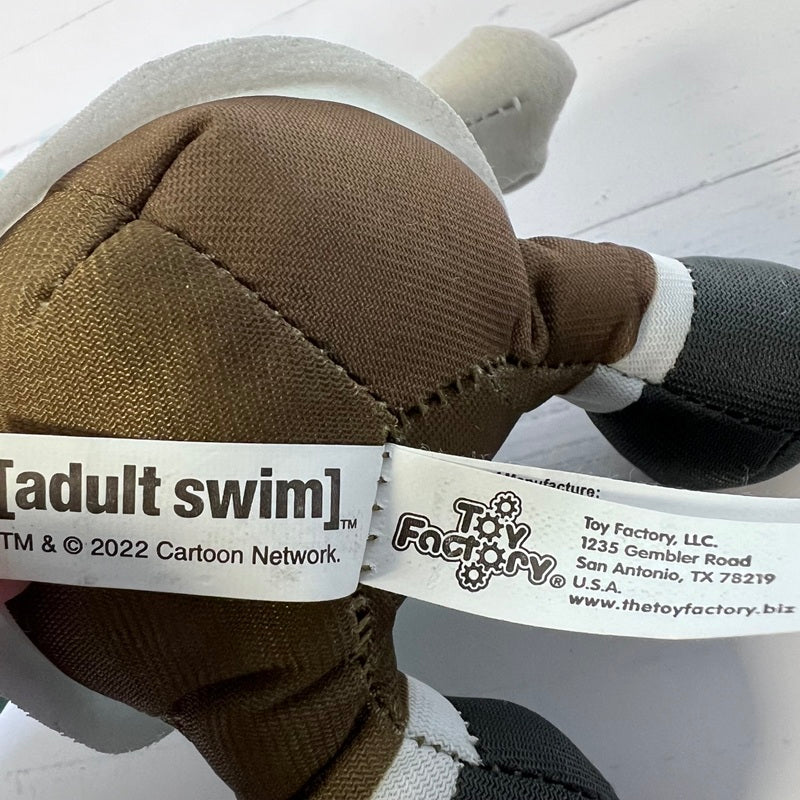 Close-up of a plush toy with 'adult swim' and 'Toy Factory' labels.