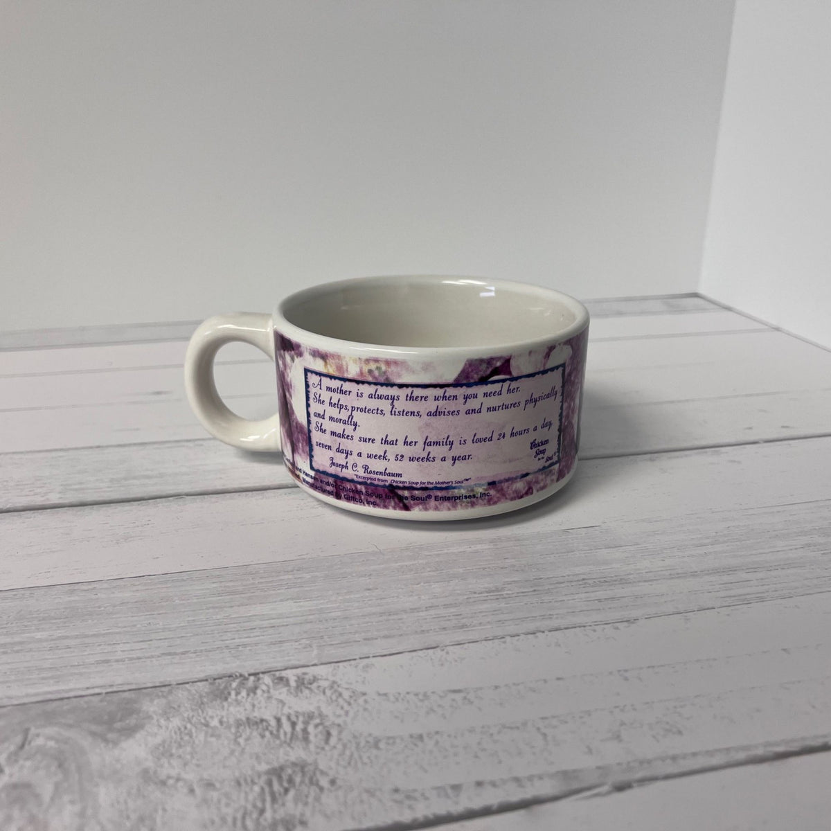 White mug with purple floral design on a white wooden surface