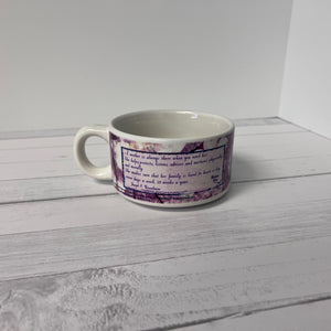 White mug with purple floral design on a white wooden surface