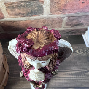 Decorative figurine with red elements on a wooden surface.