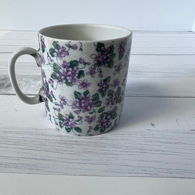 White mug with purple floral pattern on a white wooden surface