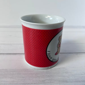 Red and white cup with 'I love you' text on a light wooden surface