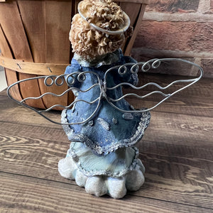 Decorative angel figurine with metal wings on a wooden surface