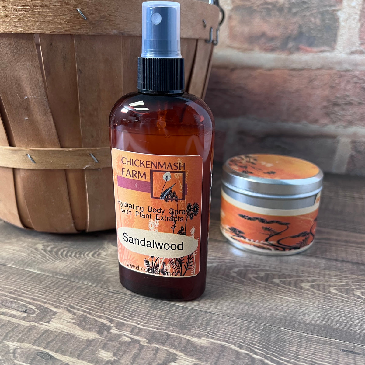 Brown bottle of Sandalwood body spray from Chickenwash Farm on a wooden surface with a basket and candle in the background.