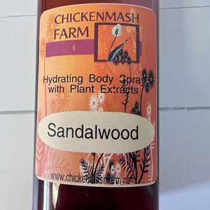 Bottle of Chicken mash Farm Sandalwood body spray on a tiled wall background