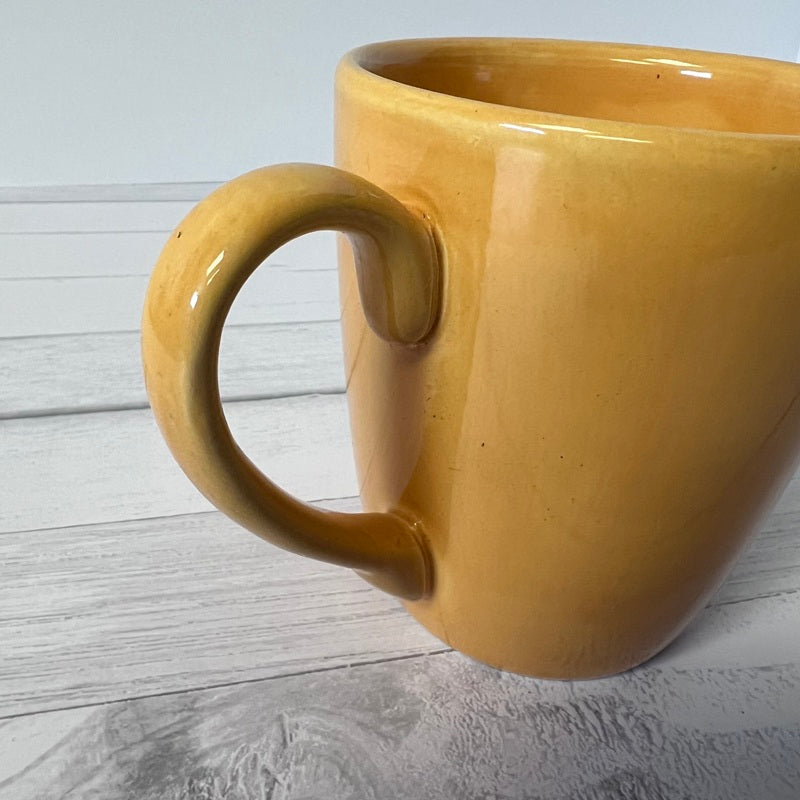 Yellow mug on a light gray wooden surface