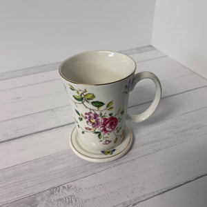Floral mug with a matching coaster on a light wooden surface
