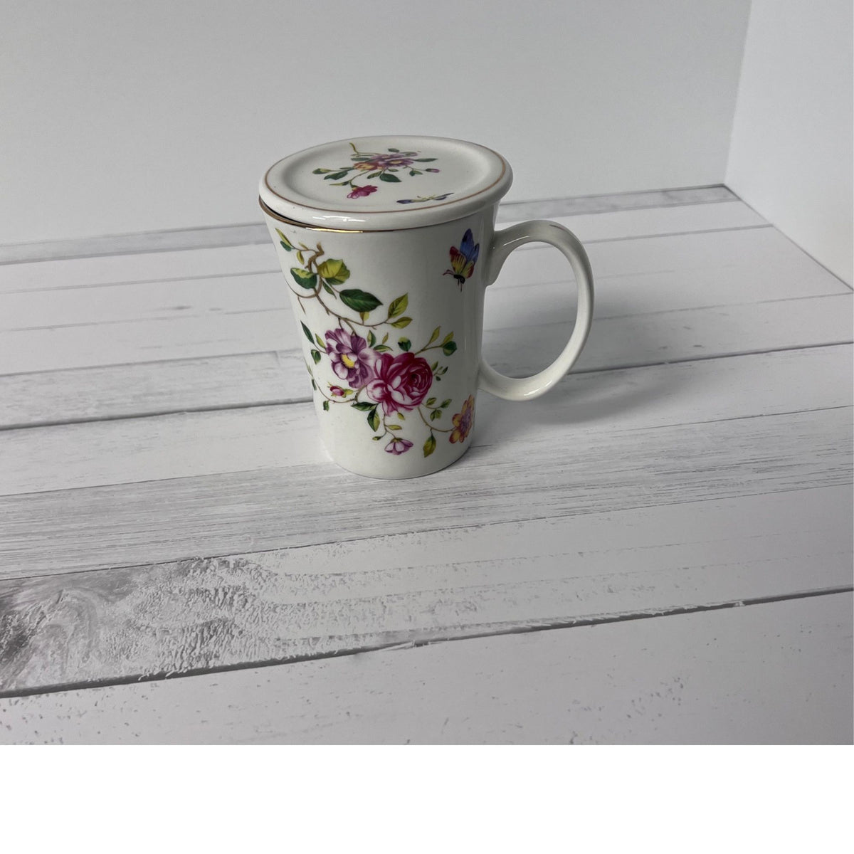 Floral mug with lid on a white wooden surface