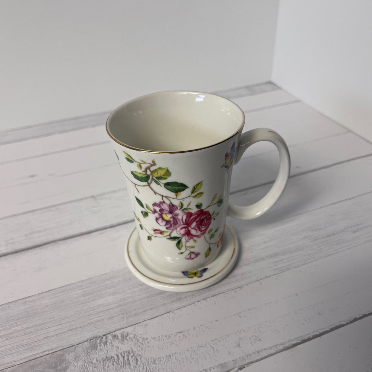 Floral mug with a matching coaster on a light wooden surface