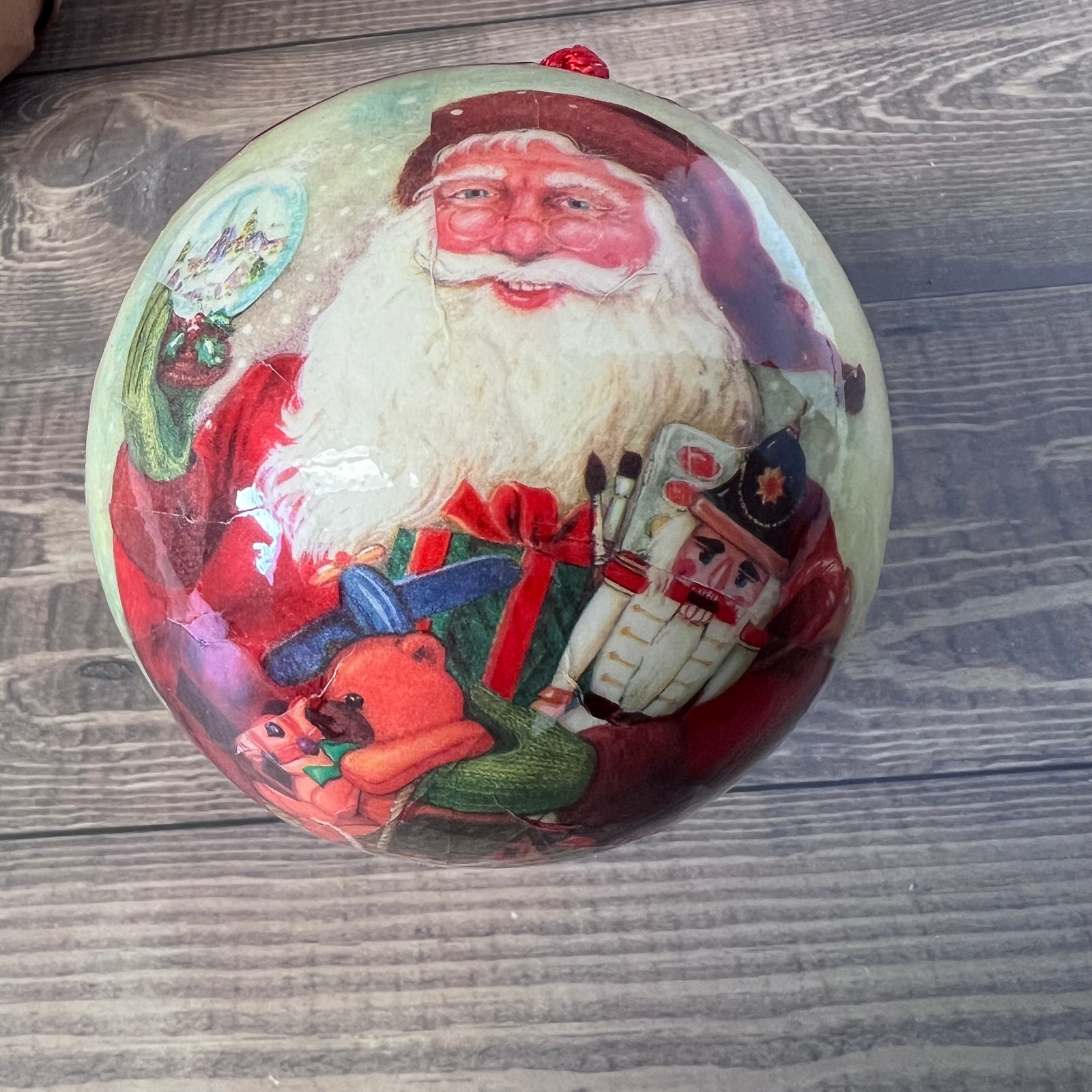 Decorative Christmas ornament with a vintage-style Santa Claus design on a wooden surface.