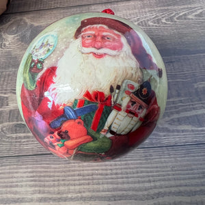 Decorative Christmas ornament with a vintage-style Santa Claus design on a wooden surface.