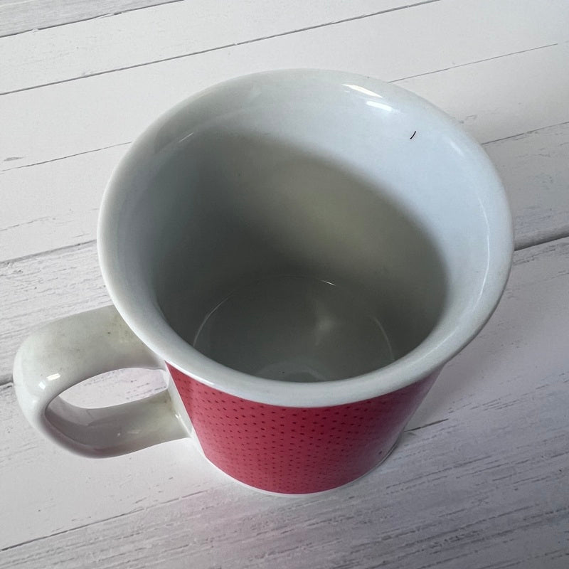 White mug with red interior on a light wooden surface