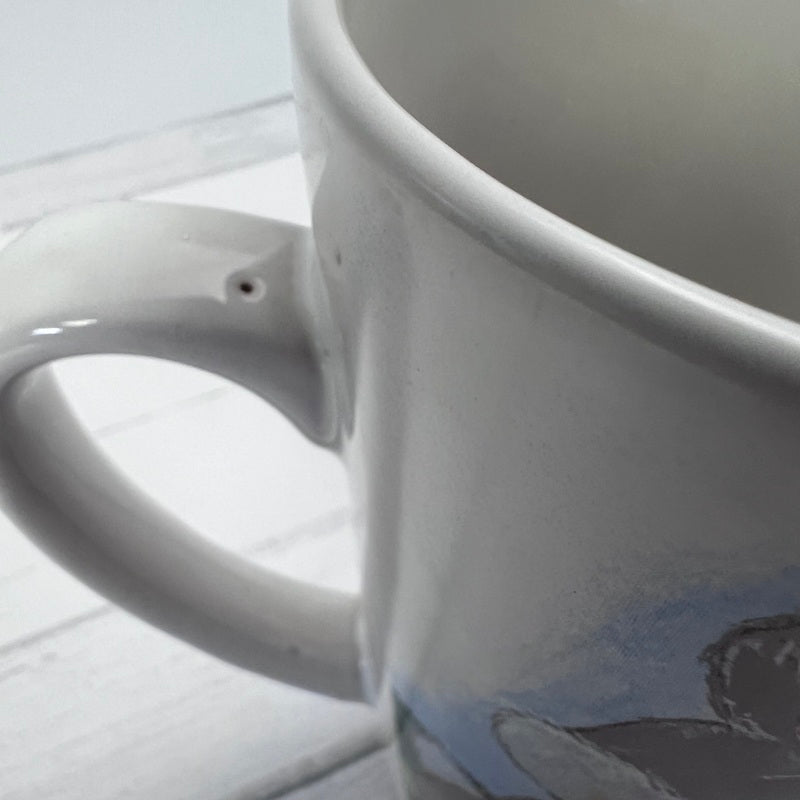 Close-up of a white ceramic mug with a handle on a light gray background