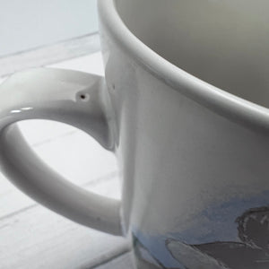 Close-up of a white ceramic mug with a handle on a light gray background