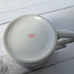 White mug with 'MADE IN KOREA' text on a light wooden surface